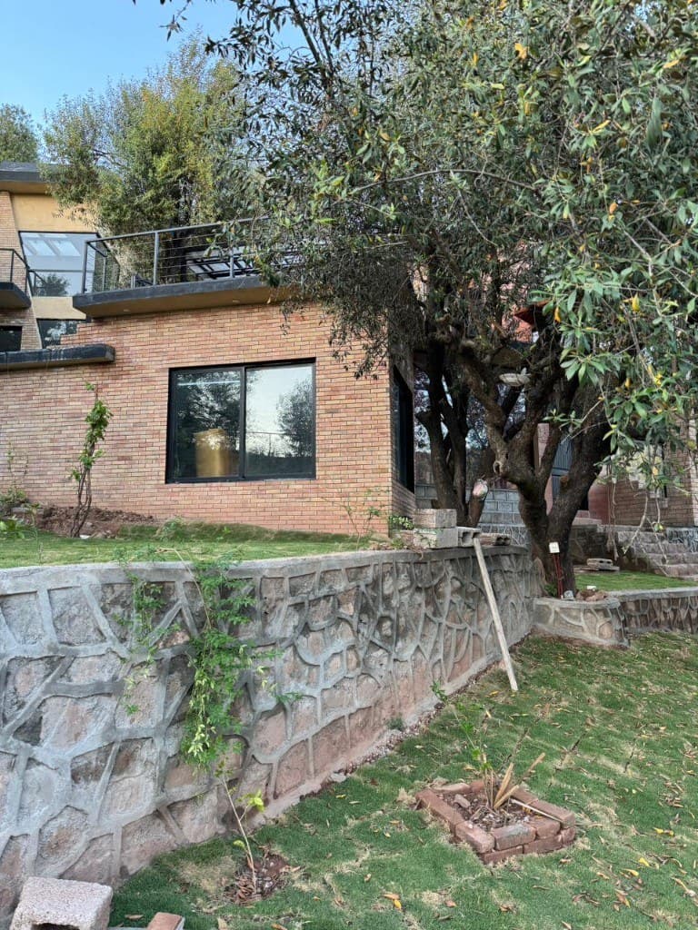 Modern brick cottage exterior with stone retaining wall at OliveHill