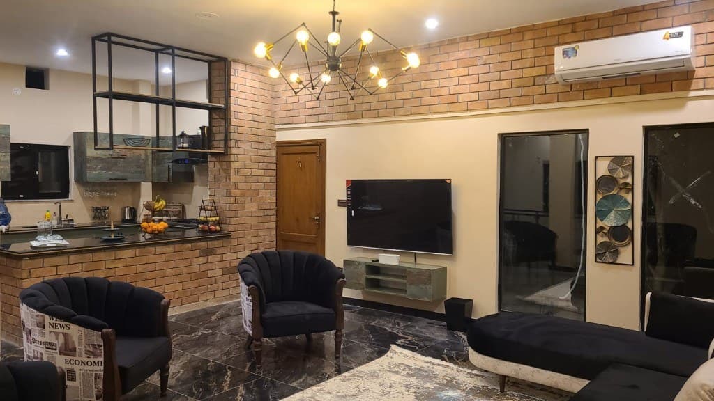Open-plan luxury living room and kitchen with brick accent wall at OliveHill